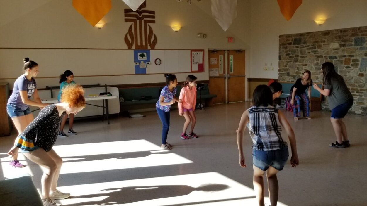 Howard County students bend knees and watch as Carrie Rose teaches creative movement