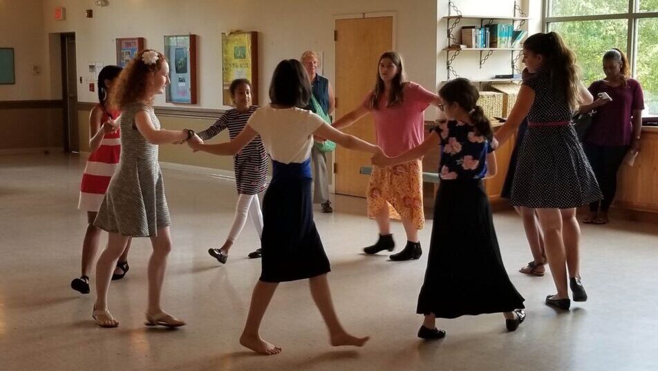 Flute-a-rama students dance together in a circle in English country dance performance